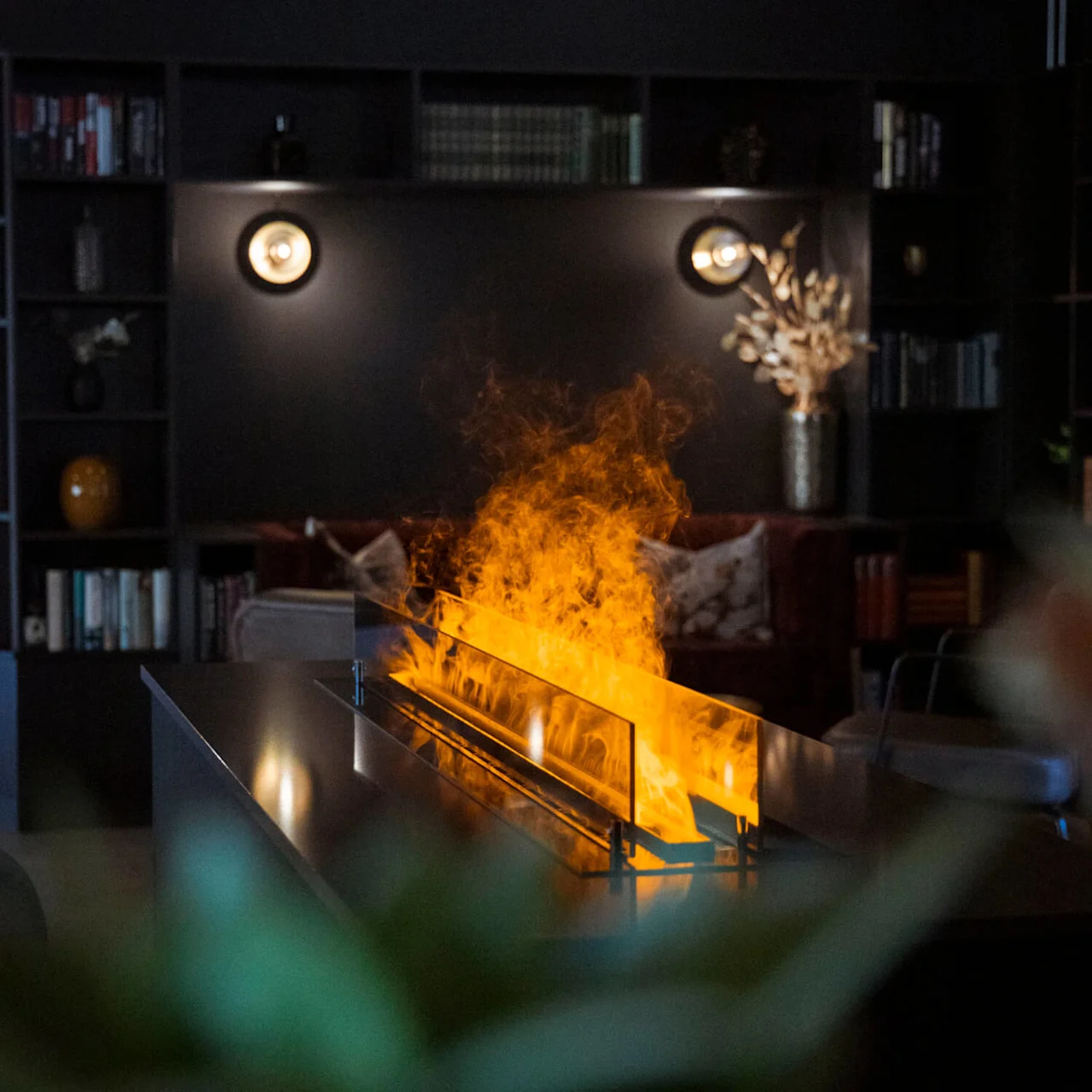 A modern fireplace with flames, set in a dark room with bookshelves.
