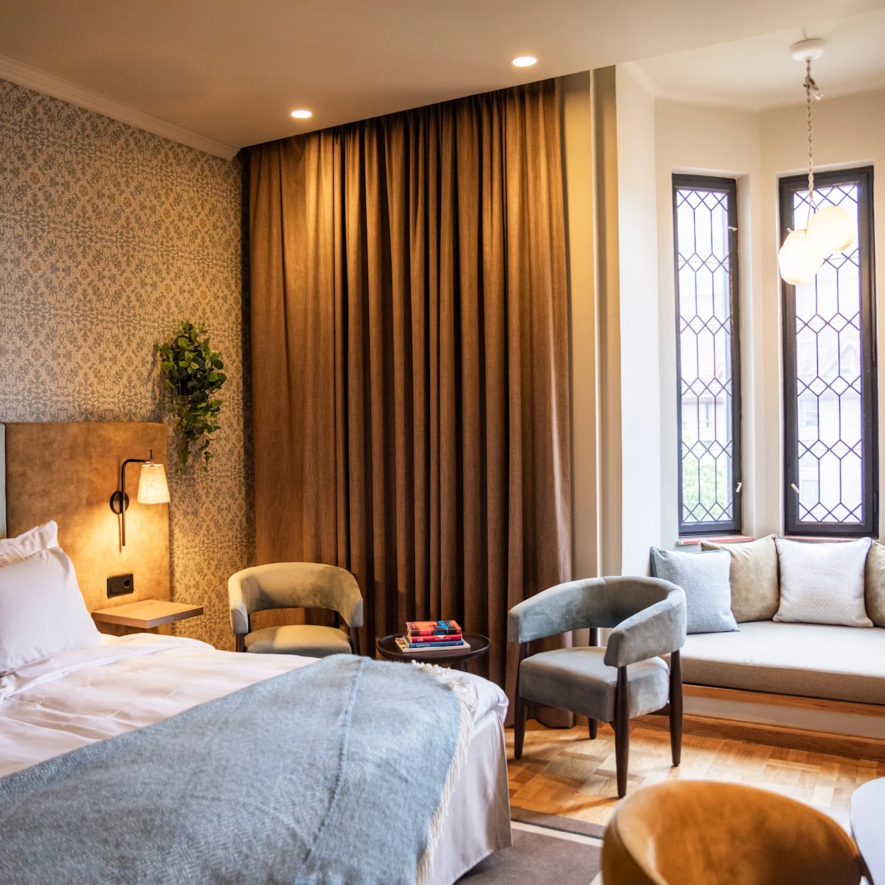 Et koselig hotellrom med en komfortabel seng, innbydende lenestoler og en lys vindusplass, perfekt for avslapning.