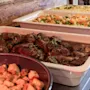 En varm buffetlinje med forskellige tilberedte retter, herunder en solid gryderet, farverige grøntsager og sprøde toppings.