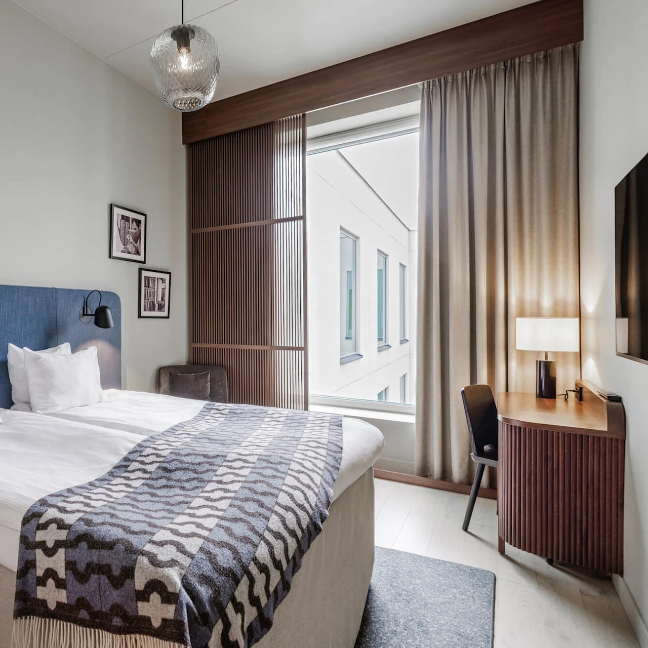 A neatly arranged hotel room with a double bed, ambient lighting, and modern decor, showcasing comfort and simplicity.