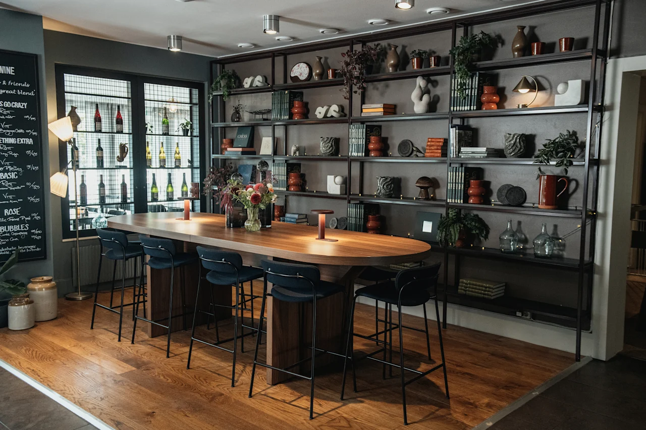 En mysig baravdelning med ett långt träbord, barstolar och hyllor fyllda med inredning. En meny listar drycker som vin, rosé och bubbel.