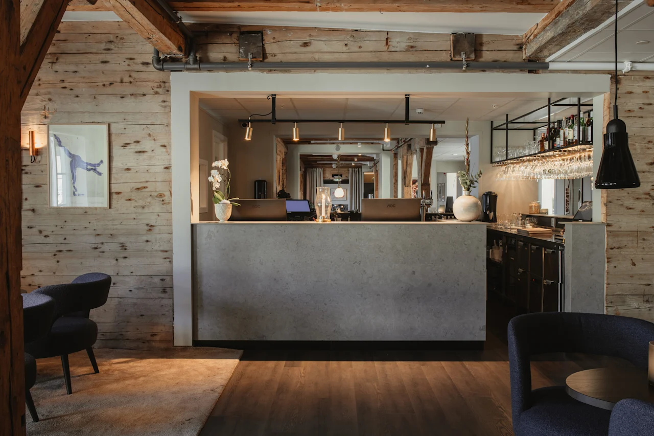 Et indbydende hotelreceptionsområde med en moderne disk, computere og en bar, med rustikke trævægge og synlige bjælker.