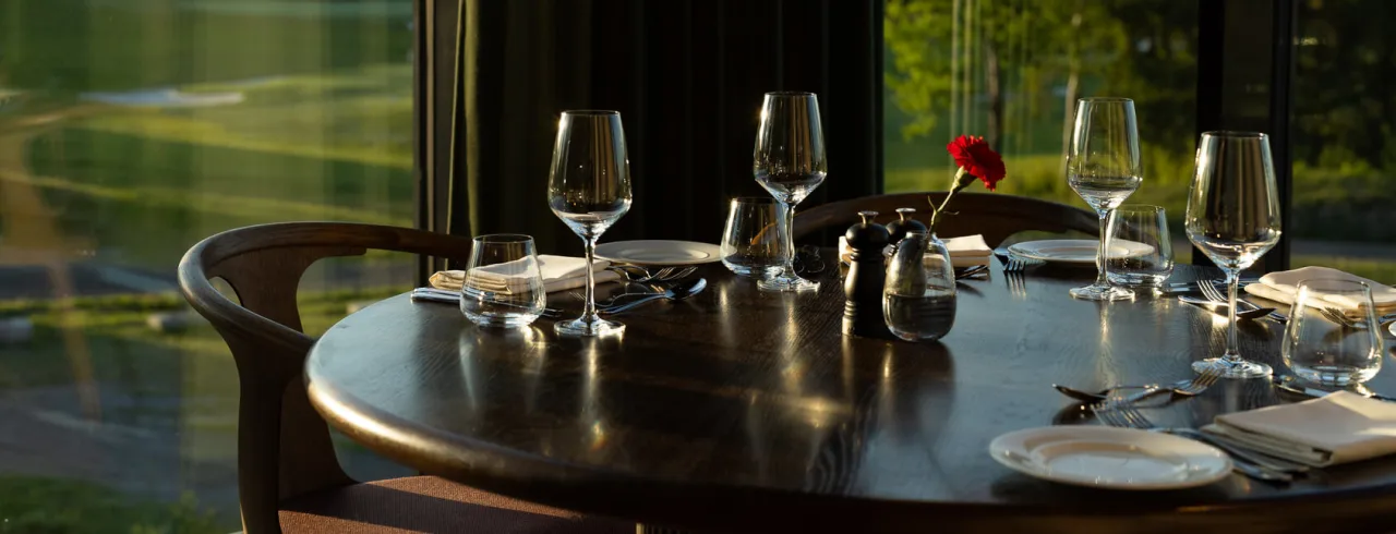  wine glass on set table in restaurant on table with golf course in background