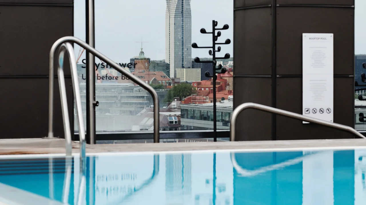 Takbasseng på Clarion Hotel Post med utsikt over byens silhuett. Skilttekst: Dusj før bading. Takbasseng.