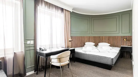 Comfort Hotel Linköping City huone, jossa on mukava sänky, työpöytä ja kirkkaat ikkunat.