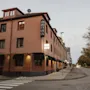 A brick hotel building on a street corner with a HOTEL sign, Home Hotel Kung Oscar. Trees line the street under an overcast sky.