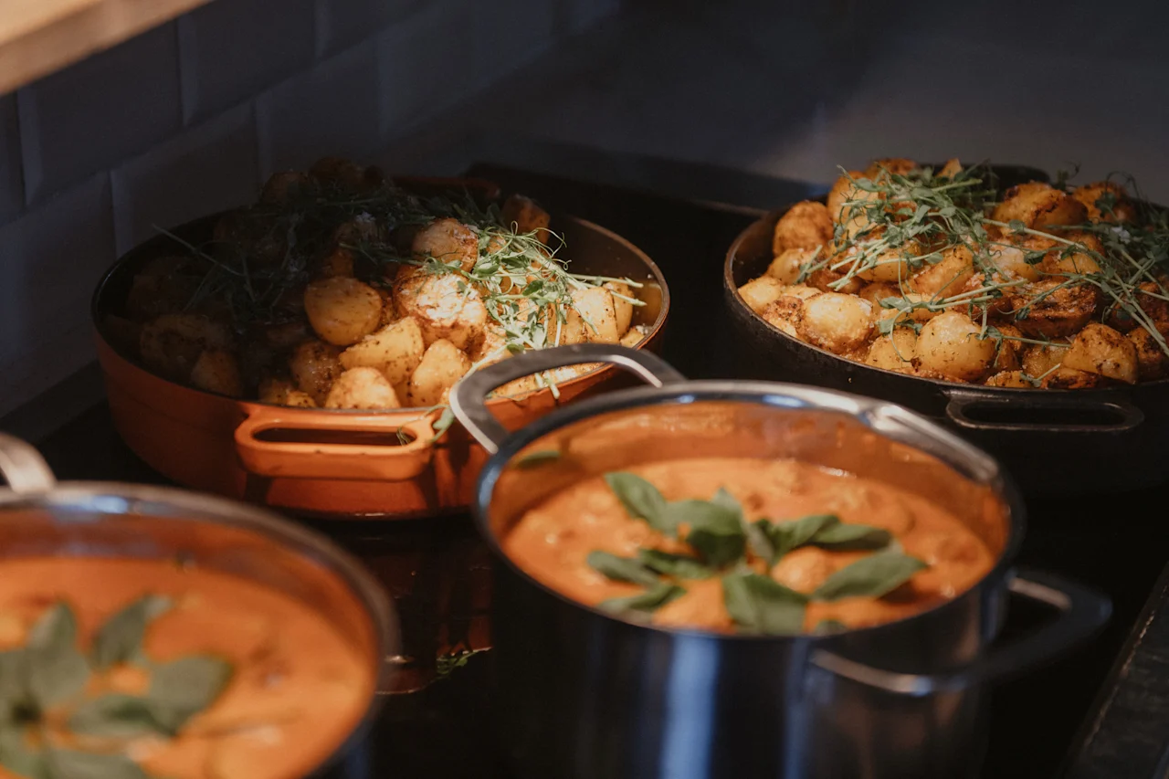 En varm matutställning med stora serveringsfat med rostad potatis och grytor med krämig sås, garnerade med färska örter.