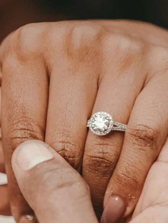 To hender forsiktig flettet sammen, den ene prydet med en glitrende forlovelsesring, symboliserer kjærlighet og engasjement.