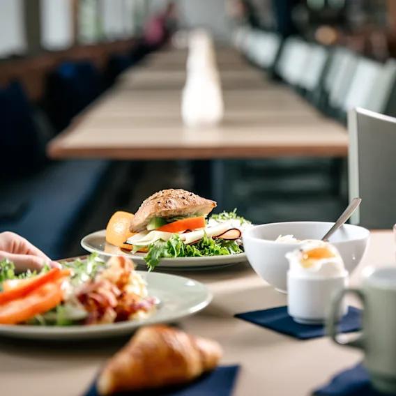 A delicious breakfast spread with sandwiches, eggs, and coffee served on a restaurant table.