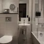 A well-appointed bathroom featuring a toilet, sink with mirror, and a shower-bathtub combination. Ready for use.
