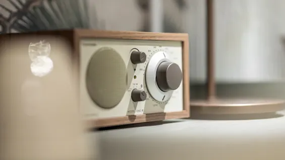 Tyylikäs radio puukehyksellä ja viritysnupuilla, mikä viittaa rentouttavaan tunnelmaan. Näkyvä teksti: MODEL ONE BT.