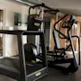 Et lyst og indbydende fitnessområde med moderne træningsudstyr og en træsauna, perfekt til en forfriskende træning.