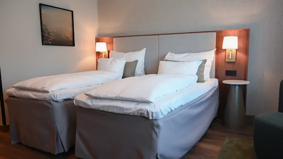 Et komfortabelt hotellrom med to pent oppredde enkeltsenger, klart for gjester å slappe av.