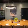 Et moderne møterom med et stort trebord, brune stoler, en sirkulær lampe og et abstrakt maleri på en grønn vegg.