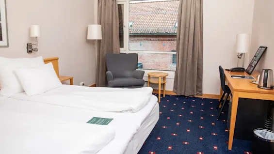 Standard doubleromm at Home Hotel Bryggen, with made bed and workspace. 