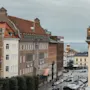 En gatuvy i Helsingborg med historiska byggnader, parkerade bilar och en glimt av havet och en fyr. Hotel Grand är synligt.