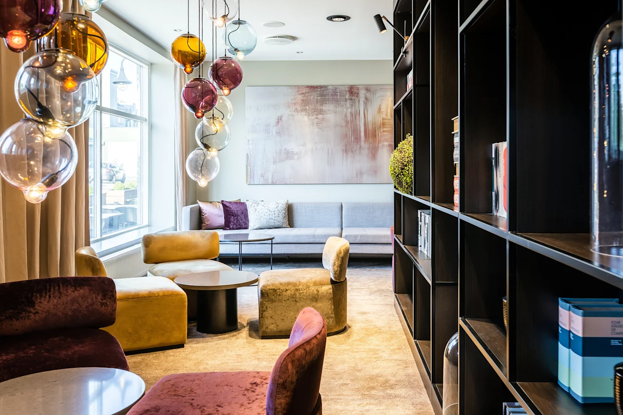 A stylish and inviting lounge area with colorful globe lights, comfortable seating, and a large window, perfect for relaxation.