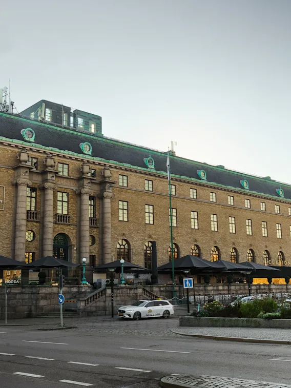 Exteriör vy av Clarion Hotel Post, en ståtlig byggnad med grönt tak och uteserveringar, intill en gata.
