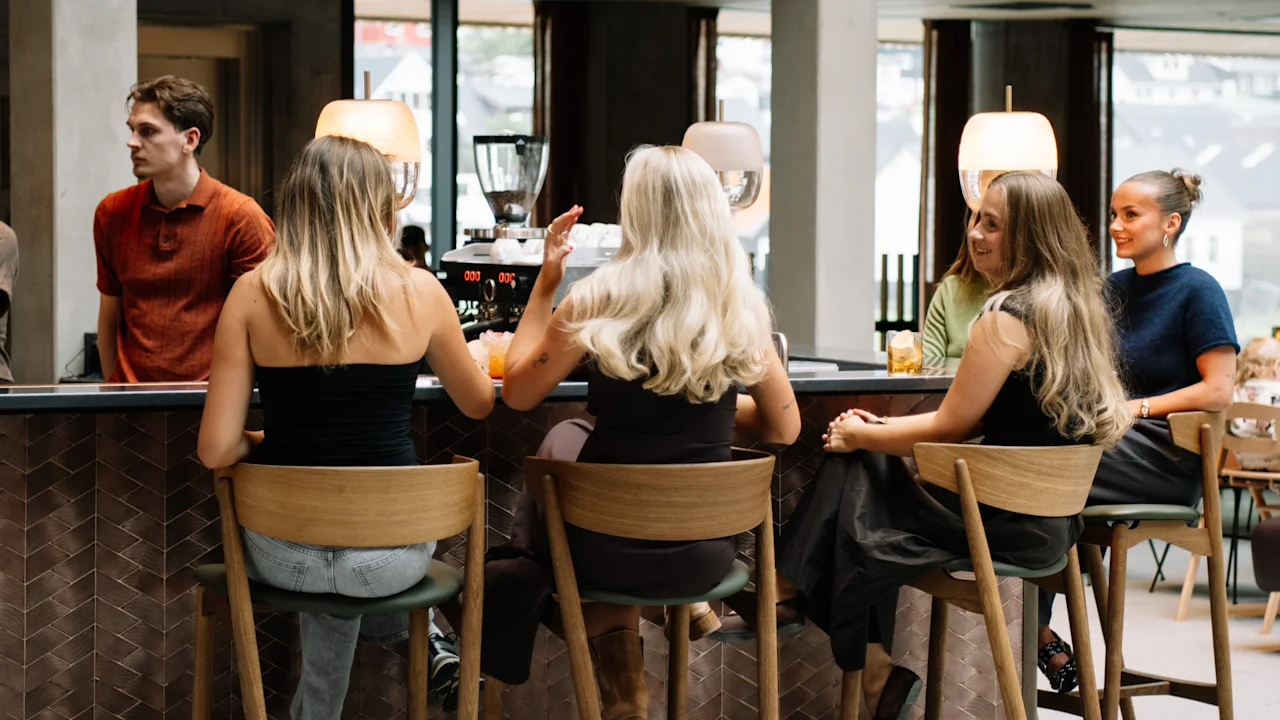 Gæster der hygger sig med drinks og samtale i den stilfulde bar på KG Hotel.
