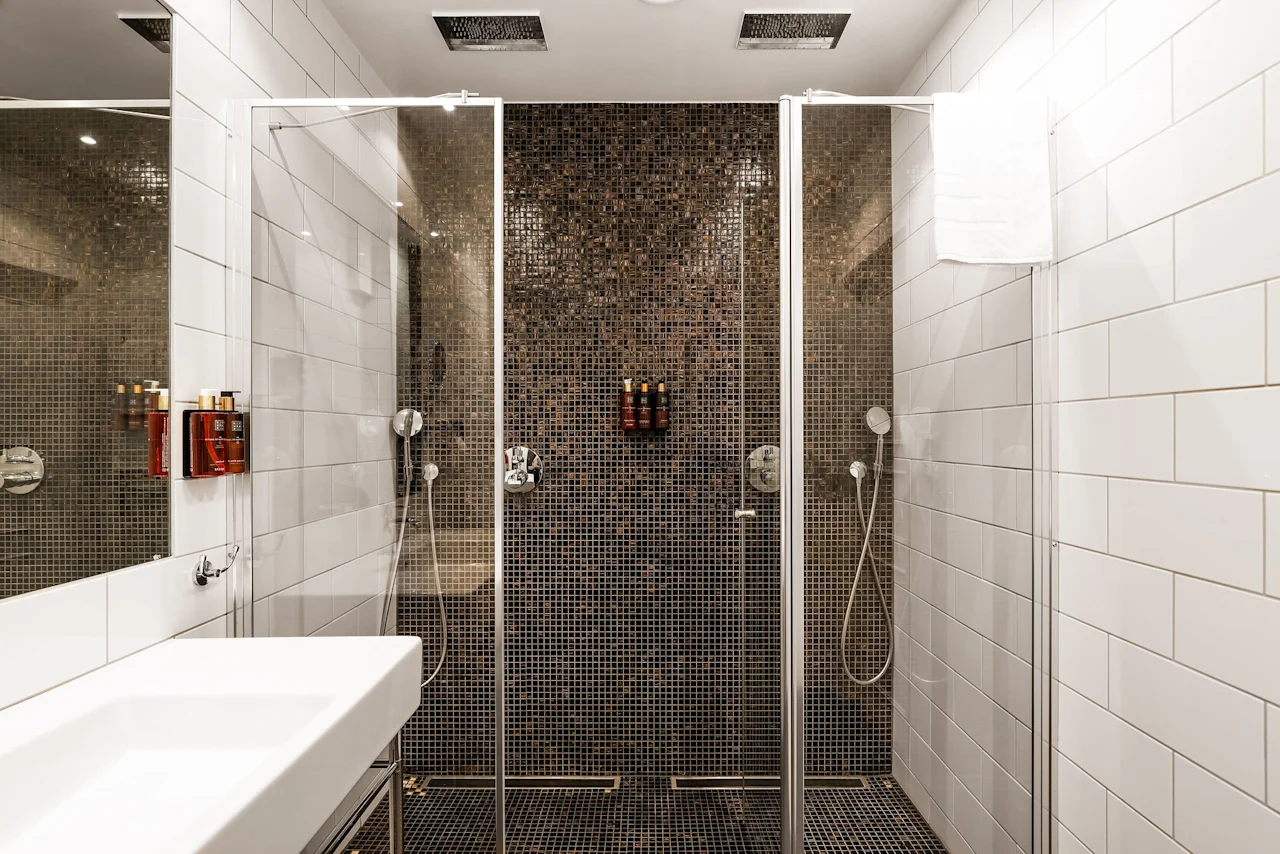 Moderne bad på Comfort Hotel Linköping City med romslig dusjområde, mosaikkfliser og elegant servant.