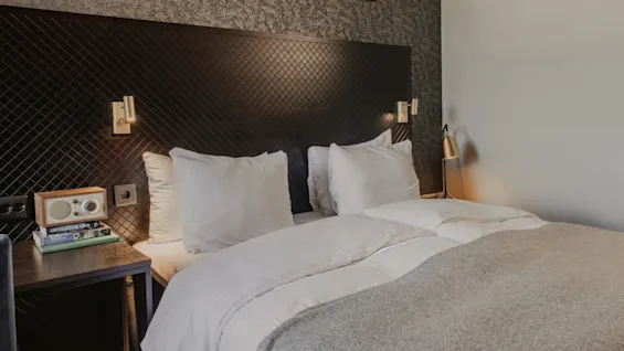 Ett bekvämt och stilfullt hotellrum på Home Hotel Grand, Helsingborg, med en säng, sängbord och dekorativ karta.