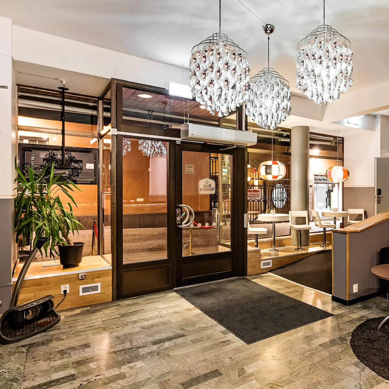 Et hotellfoaje med moderne dekor, komfortable sitteplasser og et frokostområde i et innbydende, godt opplyst rom.