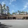 Suuri hotelli, jossa lukee "Quality Hotel Sveitsi" näkyvästi julkisivussa. Ympärillä laaja ajotie ja puita, taustalla kirkas taivas.