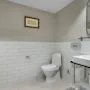A clean and modern bathroom featuring white subway tiles, a toilet, a sink with a mirror, and fresh towels.