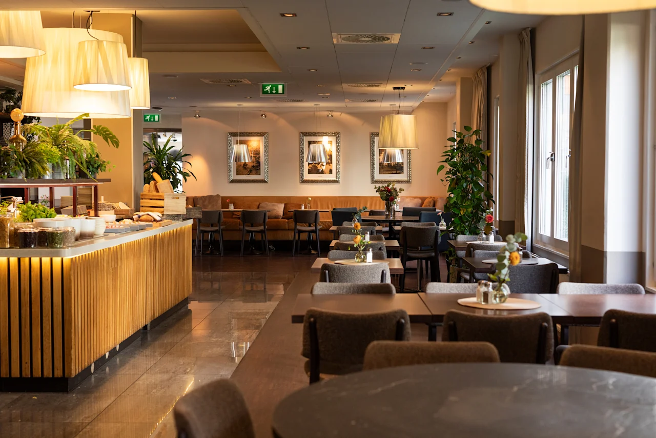 En varm och inbjudande hotellmatsal med en buffédisk, bord och stolar, redo för gäster att njuta av en måltid.