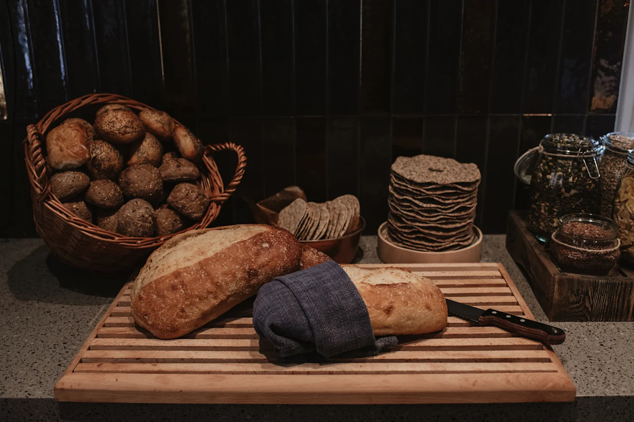 Et herlig utvalg av ferskt brød, rundstykker og kjeks, akkompagnert av glass med frø, klart for et deilig måltid.