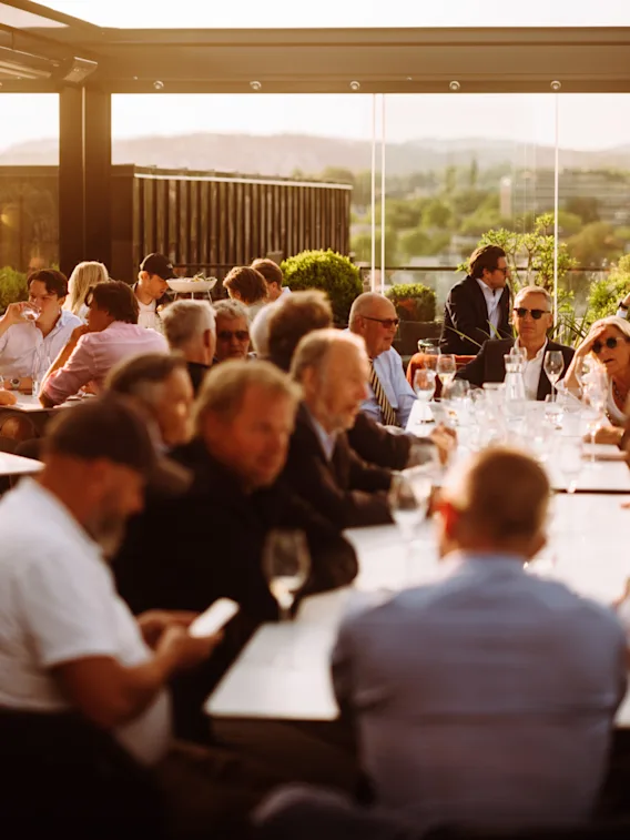 A group of people enjoying an evening meal and conversation on a sunny outdoor terrace at The Thief.