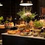 Et vakkert arrangert buffébord med et utvalg av ferske retter, skåler og elegante blomsterdekorasjoner under varm belysning.
