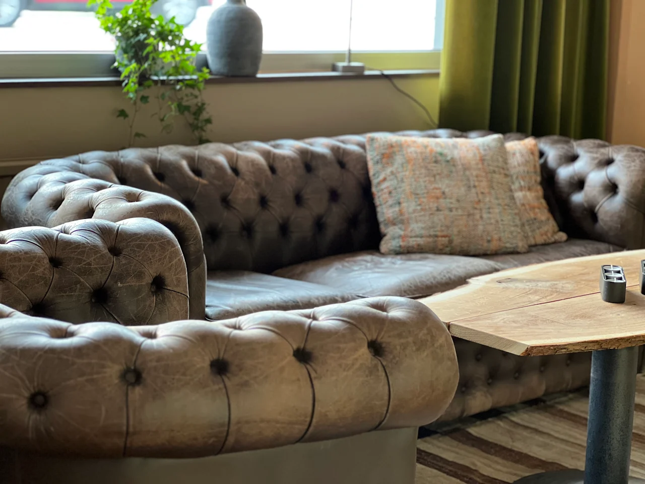 En mysig lounge på Quality Hotel Royal Corner med en lädersoffa, fåtölj och ett soffbord i trä.