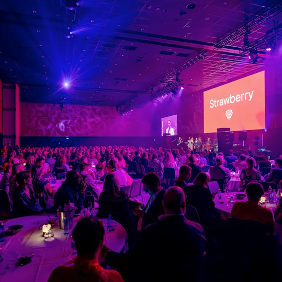 Suuri yleisö osallistuu konferenssiin Clarion Hotel Helsinki Airportissa. Näytöllä lukee 'Strawberry' lavalla.