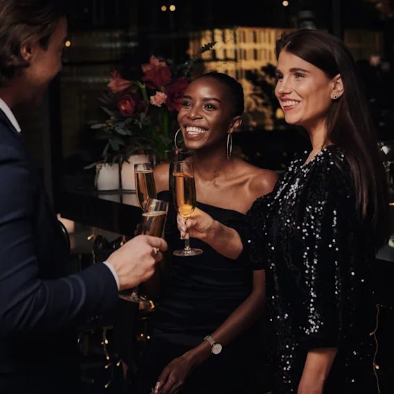 People smiling and raising a toast with champagne glasses at a festive evening event.