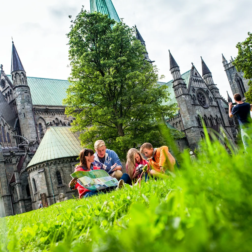Folk utforsker historiske katedralområder, noen ser på et kart, andre nyter naturen.