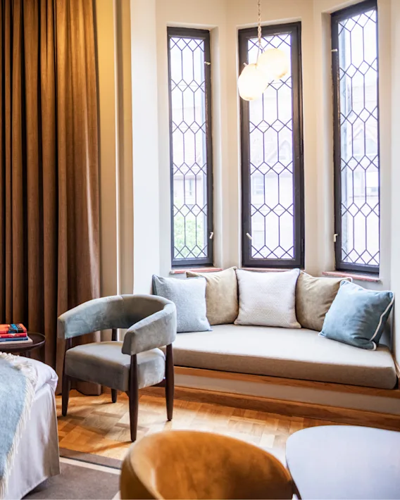 Et koselig hotellrom med en komfortabel seng, innbydende lenestoler og en lys vindusplass, perfekt for avslapning.