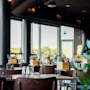 Bord med glass er satt i en moderne restaurant, med store vinduer som vender mot vegetasjon utenfor.