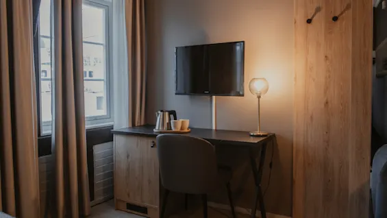 Et hyggeligt hotelværelseshjørne med skrivebord, TV og varm drikkestation, perfekt til at slappe af eller indhente opgaver.