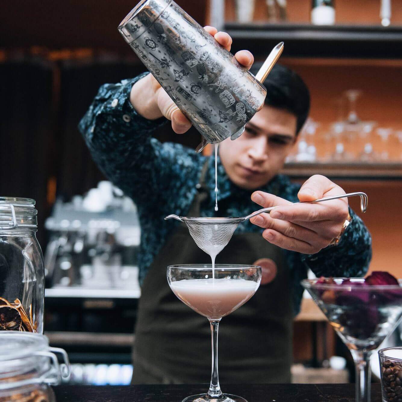 The bartender pouring up a cocktail in a glass at Clarion Hotel Wisby.