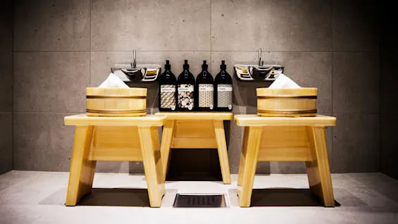 En trebenk med badetilbehør mot en betongvegg.