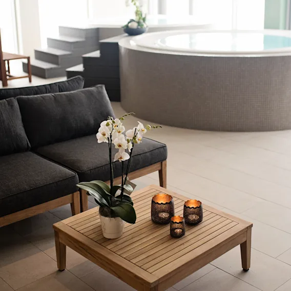 Quality Hotel Oresund – Rooftop Spa. En lugn spa-lounge med en bekväm soffa, soffbord med orkidéer och en bubbelpool.