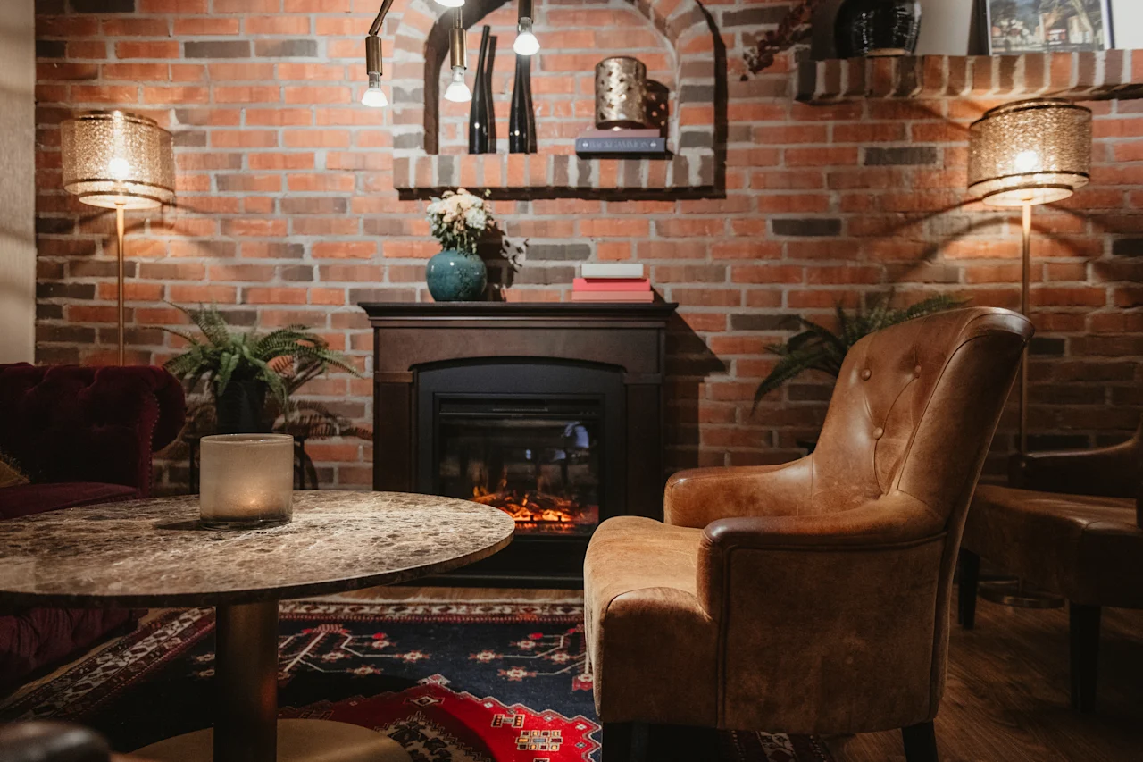 Ett mysigt rum med en tänd öppen spis, en bekväm fåtölj och varm belysning, vilket skapar en inbjudande atmosfär.