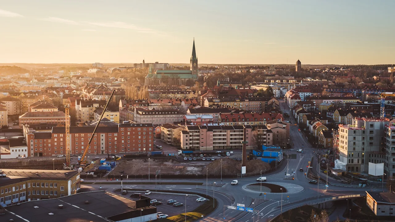 A cityscape shows buildings under a warm sunset with a prominent church spire in the middle distance and a few cars on roads, suggesting urban life.