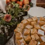 A delightful spread of square cakes, some dusted with sugar, alongside floral arrangements at Home Hotel Baltzar.