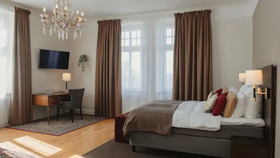 Kutsuva hotellihuone, joka on suunniteltu mukavuutta ja tuottavuutta varten, sänky, työpöytä ja valoisat ikkunat.