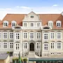 En storslået, historisk hotelbygning med rødt tegltag, mange vinduer og en fremtrædende indgang. Teksten HOTEL er synlig.
