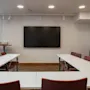 A modern meeting room at Home Hotel Uppsala with a large screen, U-shaped table, and chairs, ready for presentations.
