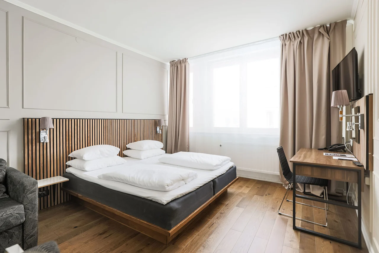 Et lyst og moderne hotellrom på Comfort Hotel Linköping City med en komfortabel seng, et skrivebordsområde og et stort vindu.