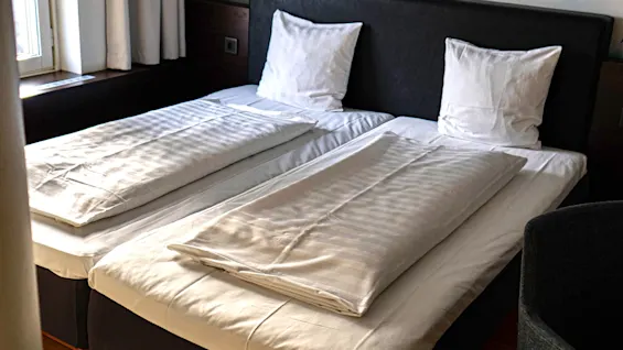 Ett hotellrum med musiktema, med två enkelsängar och en stor väggmålning av en lysande vintagemikrofon bakom sänggaveln.